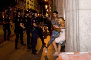 Katherina es sujetada por un amigo tras recibir un bofetón por parte del agente antidisturbios que se encuentra delante de ella. Foto: Daniel Nuevo