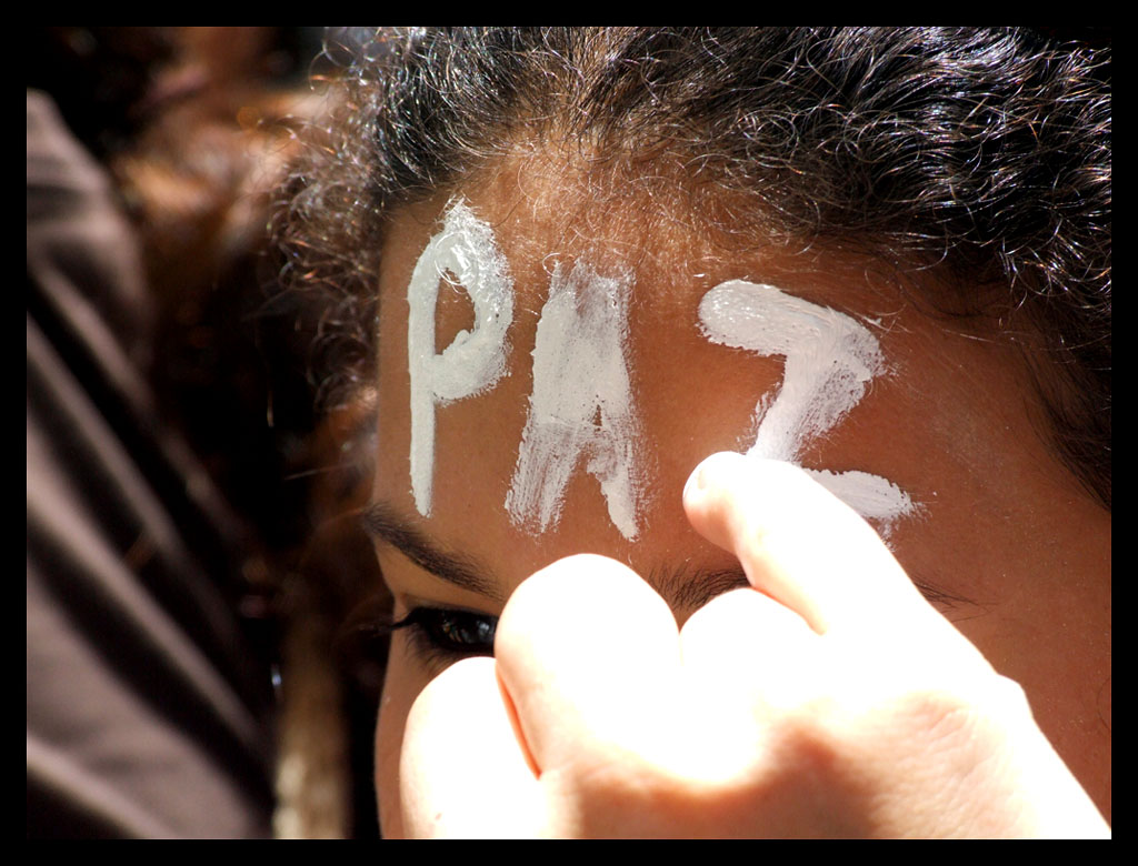 mujer se pinta la palabra paz en la frente