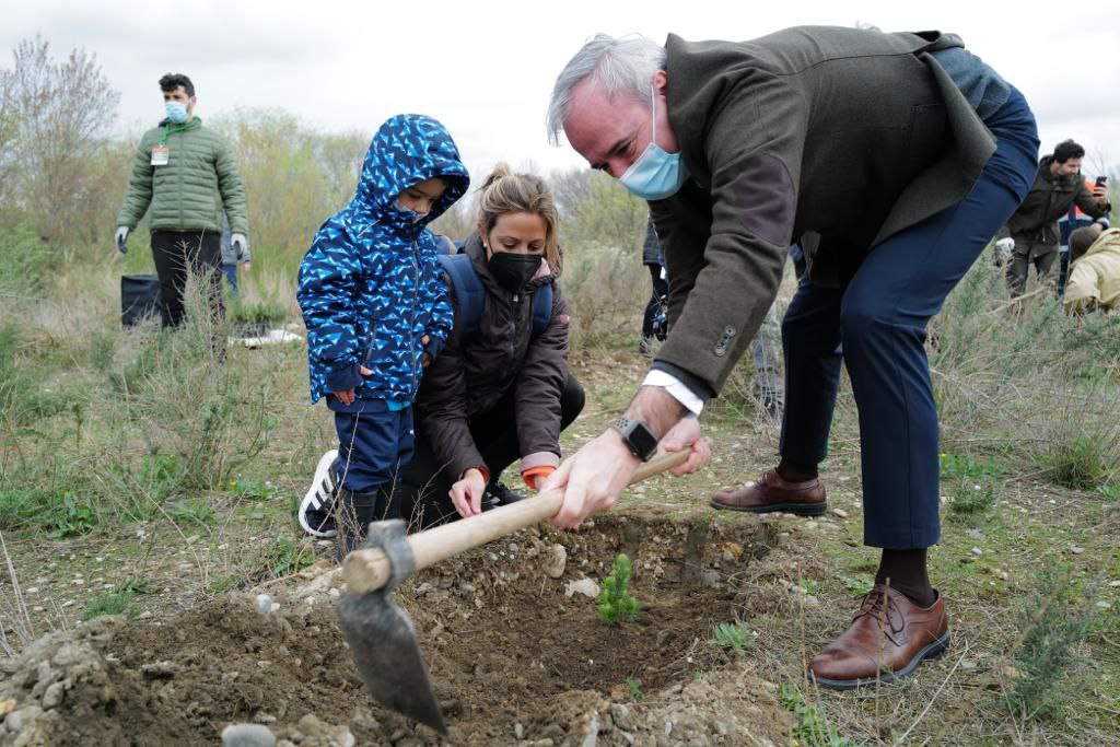El alcalde jorge azcon con una hazada le da al sueño de lo que sera el bosque de los zaragozanos con dos personas mirandole