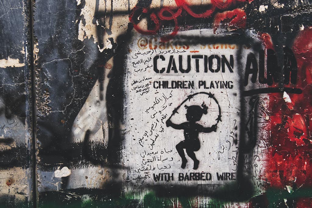 graffitii de una niña o un niño jugando a la comba con un alambre de puas en la frontera de Israel