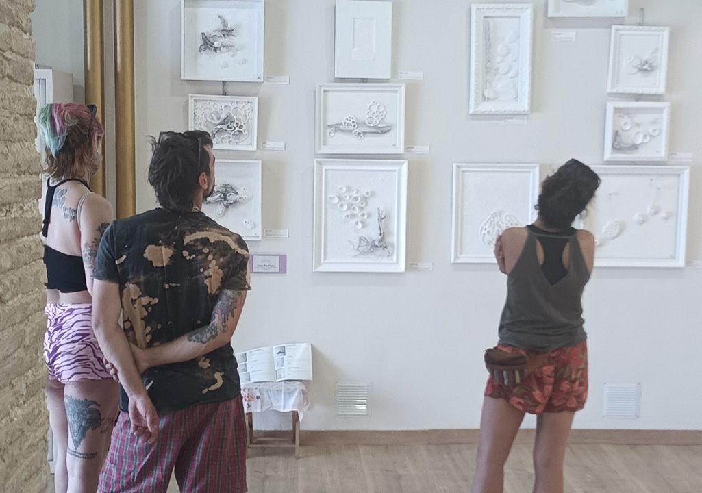 Dos mujeres y un hombre mirando una exposición de mujeres creadores en el festival de Magallón