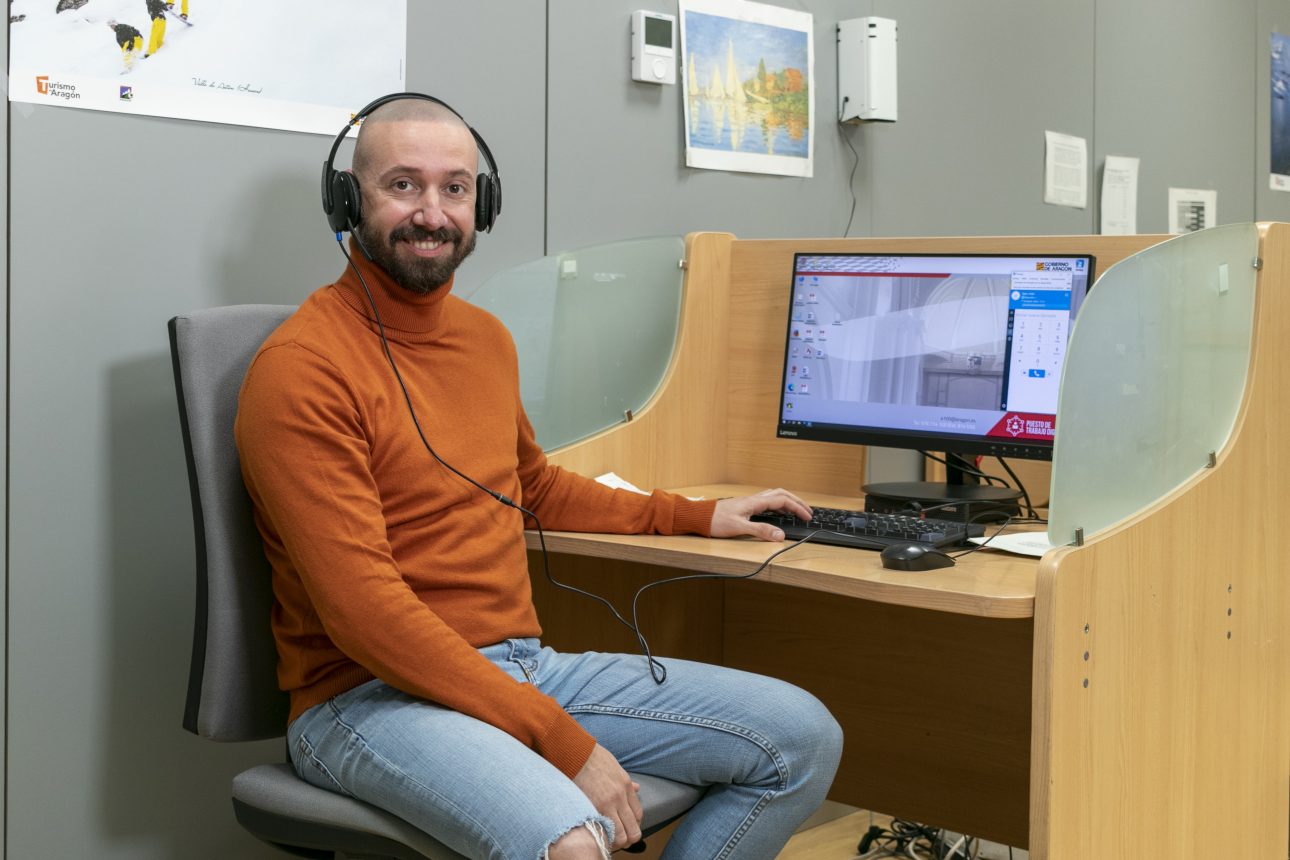 uno de los asistentes de atención telefónica en su puesto de trabajo con los cascos puestos