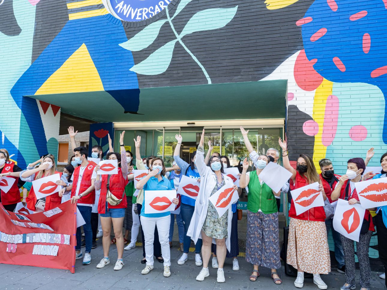 un grupo de personas frente al hospital con carteles de besos