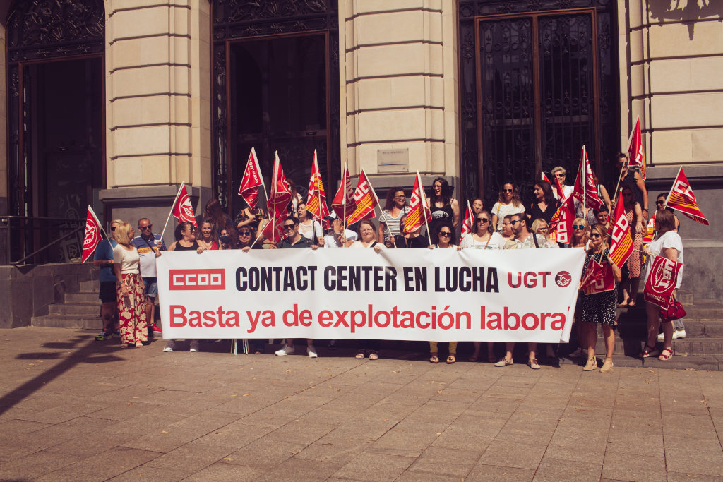 Un grupo de trabajadores de contact center en una concentración con una pancarta