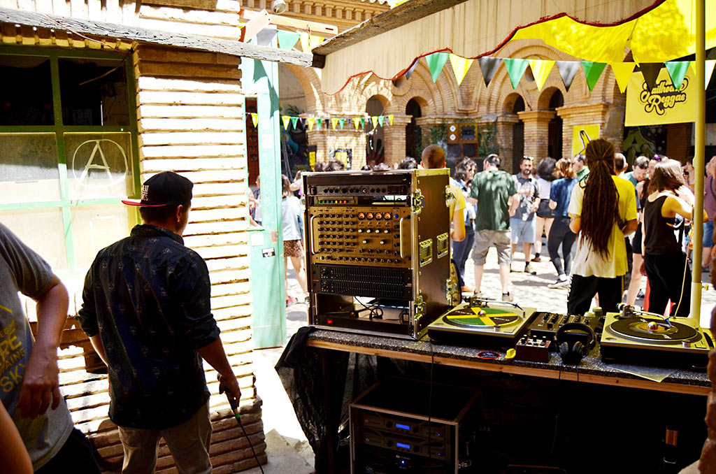 un dj de jailhouse reggae con una mesa de sonido y gente bailando de fondo