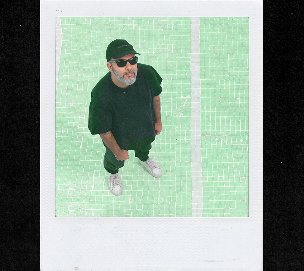 DJ2D2 con gorra y gafas de sol mirando hacia arriba con fondo verde, nuevo dj de la fiesta fokin massive