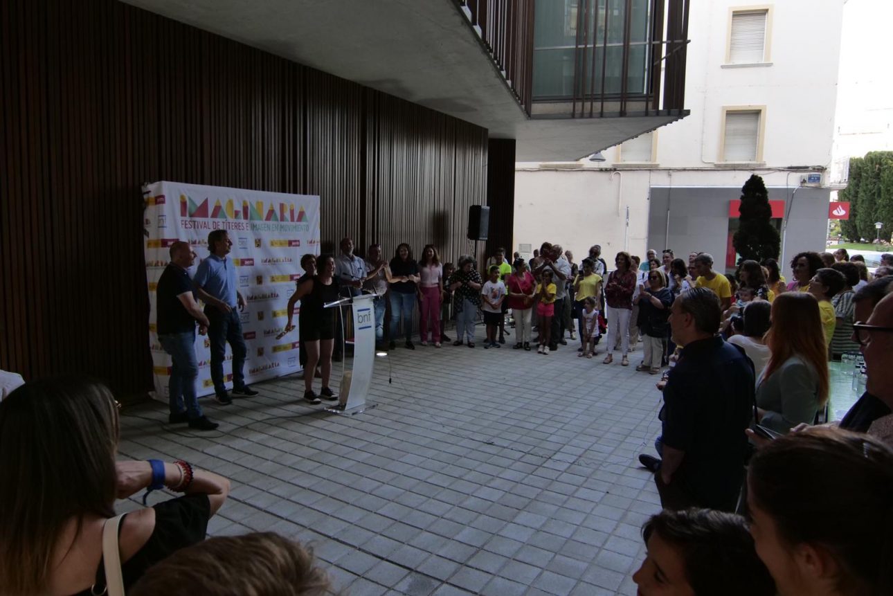 Un grupo de personas en torno a un atril en la inauguración de imaginaria