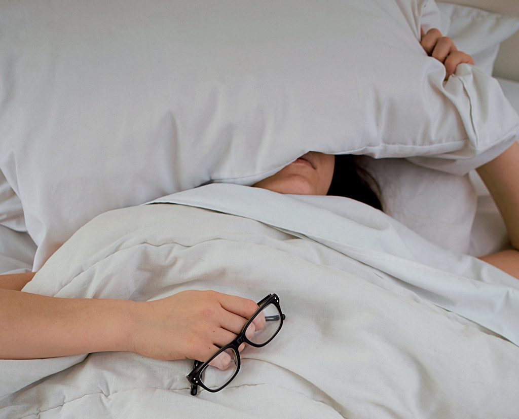 Una mujer durmiendo mal en una cama con sabanas blancas
