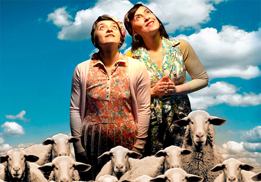 Dos mujeres rodeadas de ovejas en el cielo en una obra del festival castillo de ainsa
