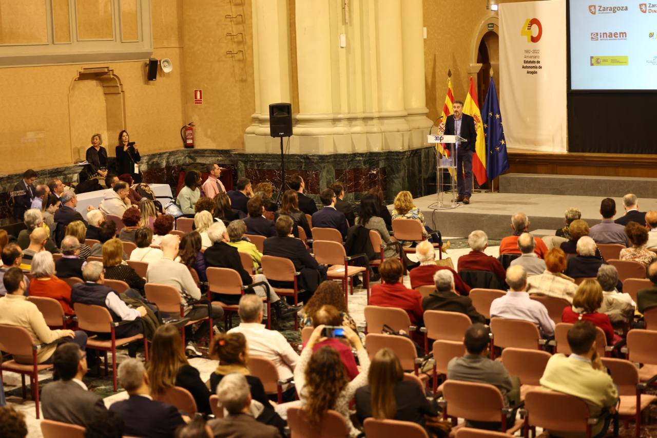 Una sala llena de gente con una mujer de la fundación picarral hablando en un atril