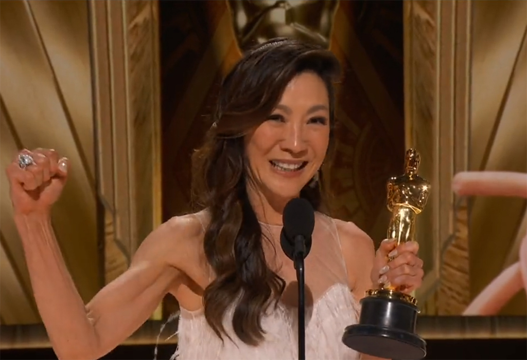 la actriz sosteniendo el oscar en una mano y sacando músculo con el otro brazo