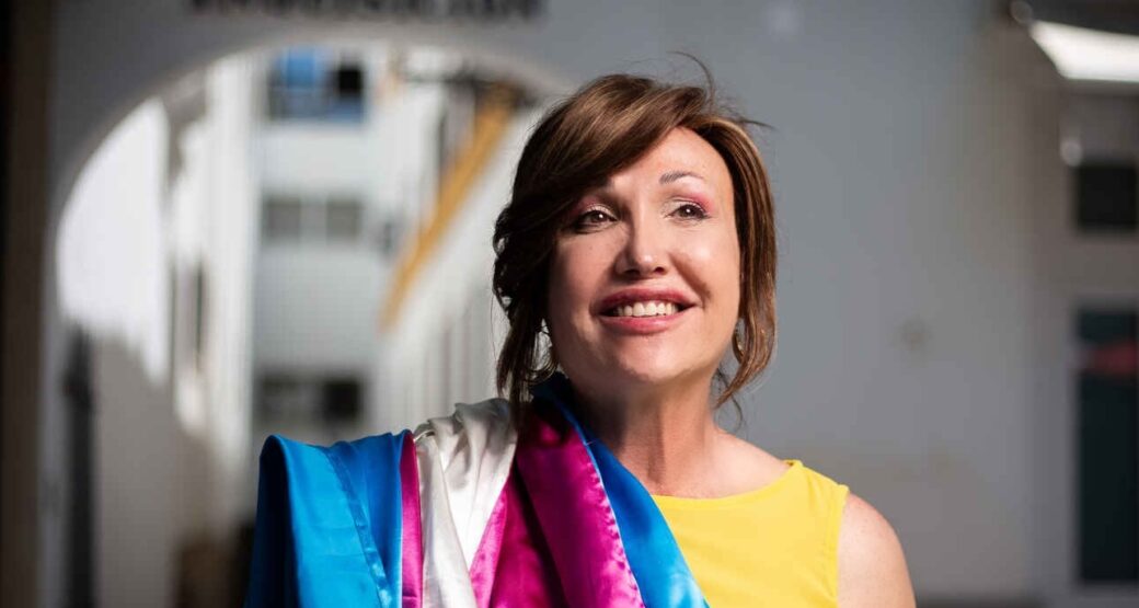 Mar Cambrollé, presidenta de la Federación Plataforma Trans, con la bandera trans al hombro en una imagen vinculada a la defensa de los derechos del colectivo LGTBIQA+.