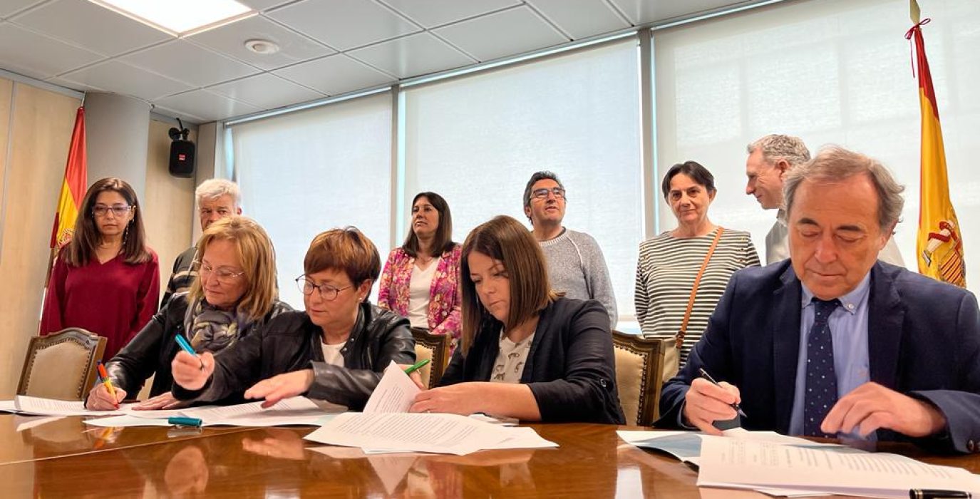 varias personas sentadas firmando el acuerdo entre el salud y los sindicatos