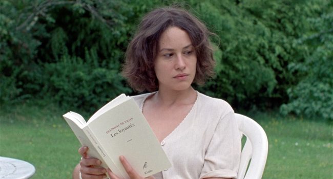 La actriz Aida Folch sostiene un libro blanco en un jardín
