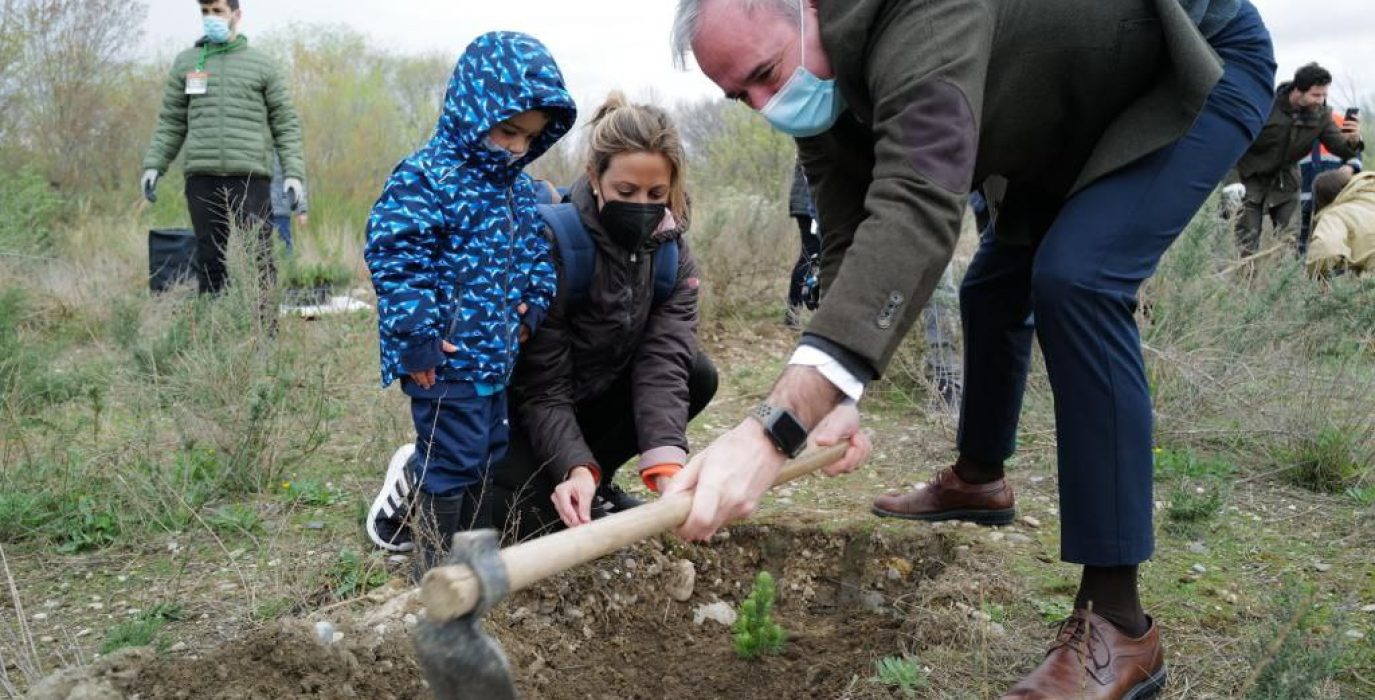 El alcalde jorge azcon con una hazada le da al sueño de lo que sera el bosque de los zaragozanos con dos personas mirandole