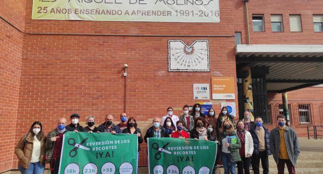 Varias personas se concentran en la fachada del IES Miguel de Molinos de Zaragoza dentro de la campaña de movilizaciones de los sindicatos STEA y CGT, con pancartas en las que se leen lemas sobre la reversión de los recortes