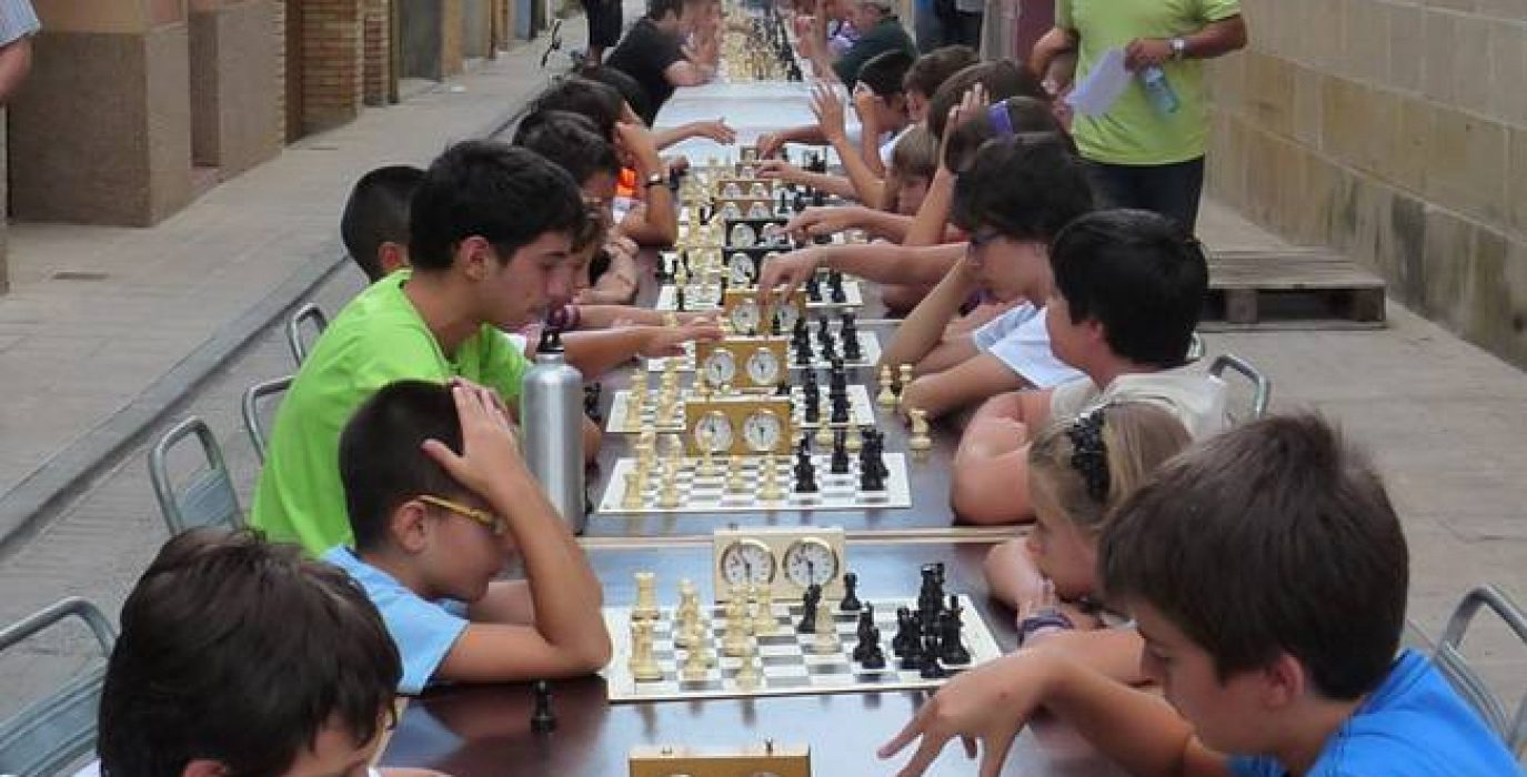 CIRCUITO DE AJEDREZ DEL SOMONTANO con niños jugando en fila en la calle al ajedrez