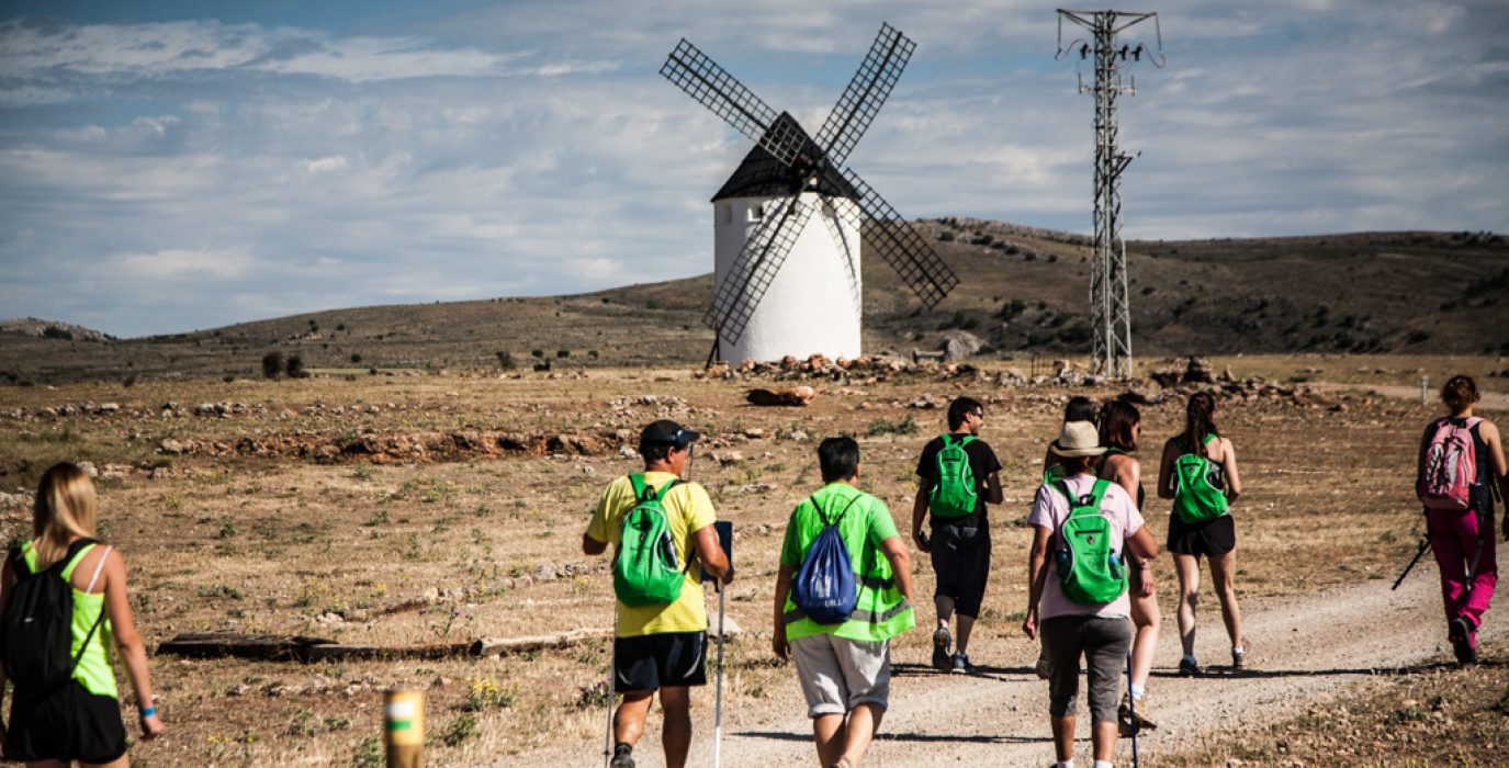 varias personas andando por una pista con un molino al fondo de comarca km0