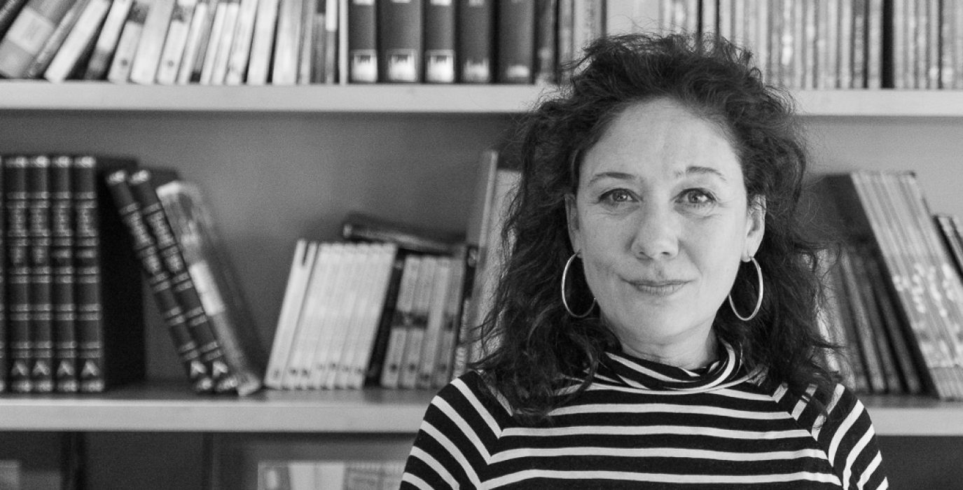 la escritora cristina fallarás posa frente a una librería sonriendo