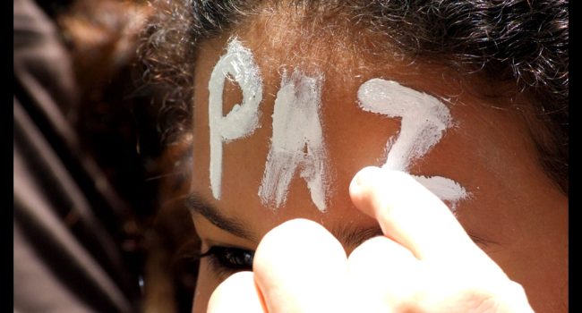 mujer se pinta la palabra paz en la frente