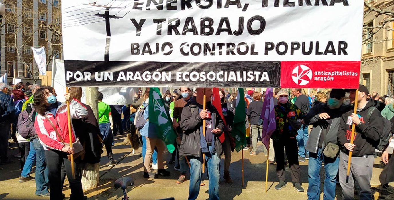 pancarta en la que pone energía, tierra y trabajo bajo control popular de anticapitalistas