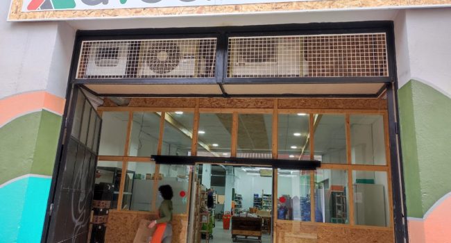 Entrada del supermercado A Vecinal con un letrero y las puertas de madera