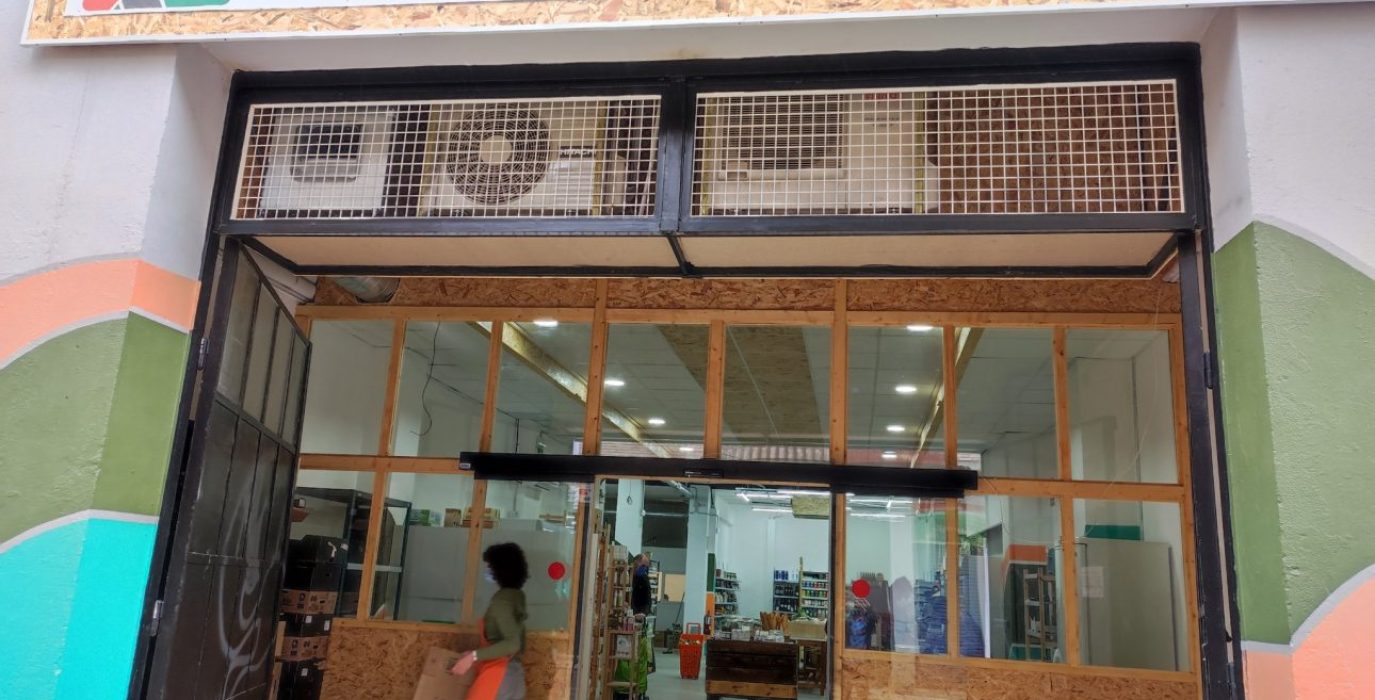 Entrada del supermercado A Vecinal con un letrero y las puertas de madera