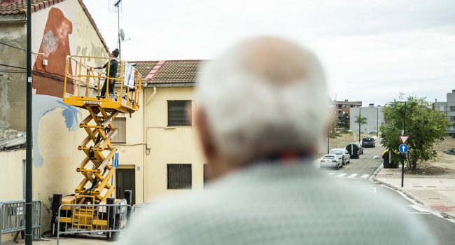 Un hombre mayor mira como pintan un mural en el asalto en santa isabel