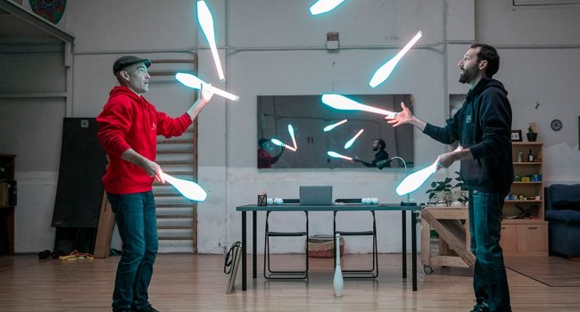 circo dos personas haciendo malabares con objetos con luz