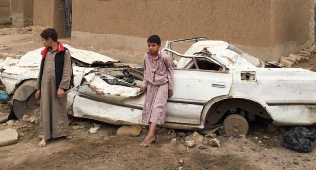 Niños ante un auto destruido en Sanaa, la capital de Yemen, durante uno de los combates en la guerra civil que padece ese país de la península arábiga desde 2015. Unicef ha documentado que cientos de miles de niños, en 30 guerras durante 18 años, han sido asesinados, mutilados, secuestrados o violados | Foto: Jonathan Dumont / PMA
