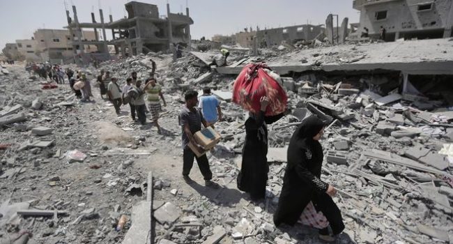Palestinos cargan con objetos personales que han logrado salvar de sus casas destruidas en los bombardeos del barrio de Beit Hanún (1 de agosto de 2014). Foto: Lefteris Pitarakis