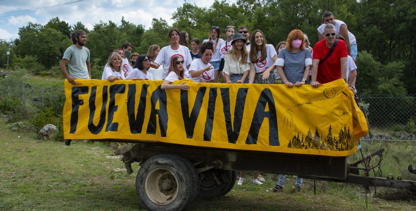 Un remolque con varias personas subidas con un cartel que pone Fueva viva
