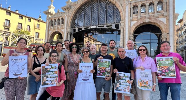 Representantes de varios colectivos aragoneses y otros ciudadanos durante la presentación del Manifiesto en la puerta del Mercado Central de Zaragoza.
