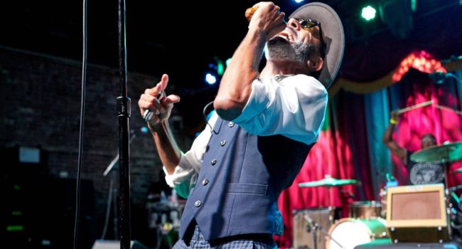 The Reverend Shawn Amos sobre un escenario cantando con el micrófono