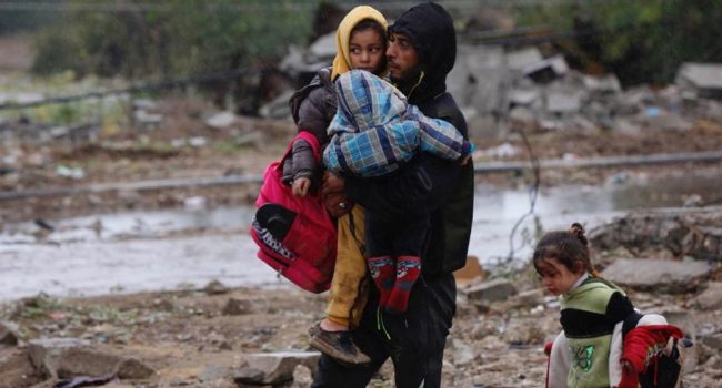 Un hombre con su hijo en brazos camina entre los escombros durante la "tregua" en Gaza | Foto: © Ashraf Amra / UNRWA