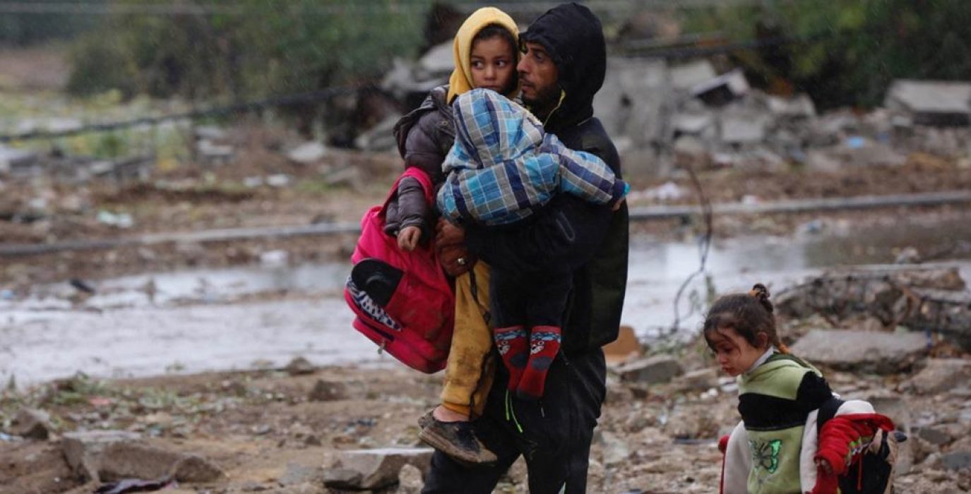 Un hombre con su hijo en brazos camina entre los escombros durante la "tregua" en Gaza | Foto: © Ashraf Amra / UNRWA