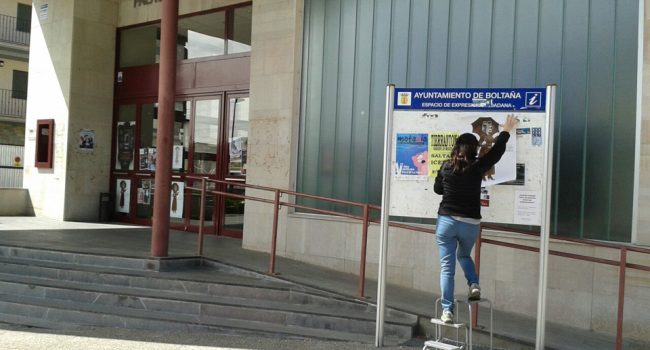 Una de las organizadoras cuelga un cartel de la Muestra frente al Palacio de Congresos de Boltaña.