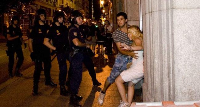 Katherina es sujetada por un amigo tras recibir un bofetón por parte del agente antidisturbios que se encuentra delante de ella. Foto: Daniel Nuevo