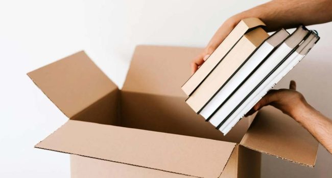 Un joven empaqueta libros en un cambio de piso. | Foto: Karolina Grabowska