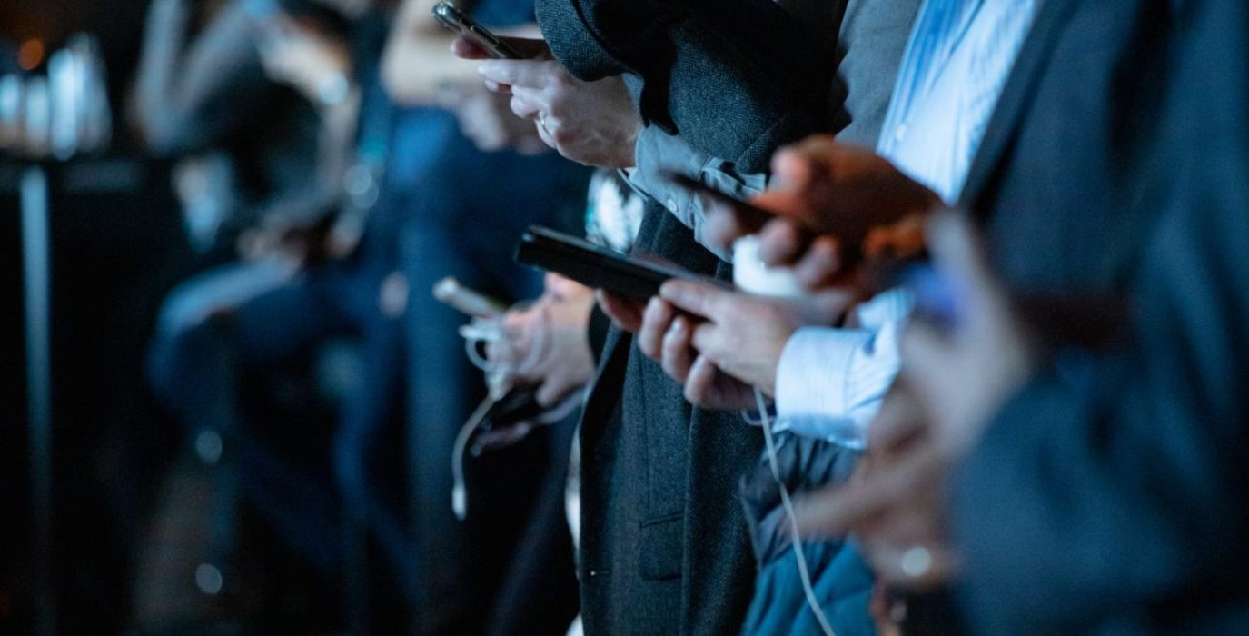 varias personas mirando el móvil para ilusrtar la noticia de los bulos