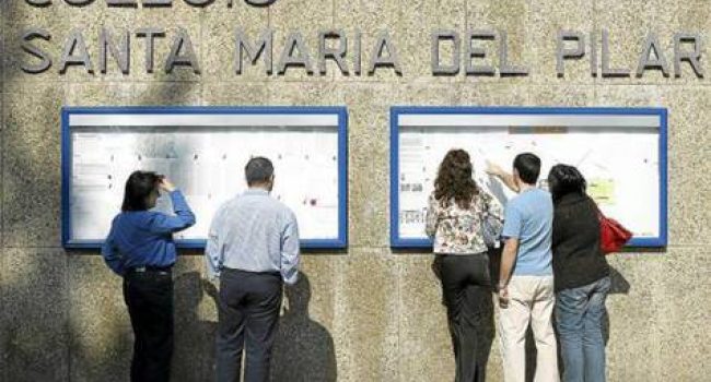 Madres y padres consultando listas en un colegio concertado que ha cubierto sus plazas.