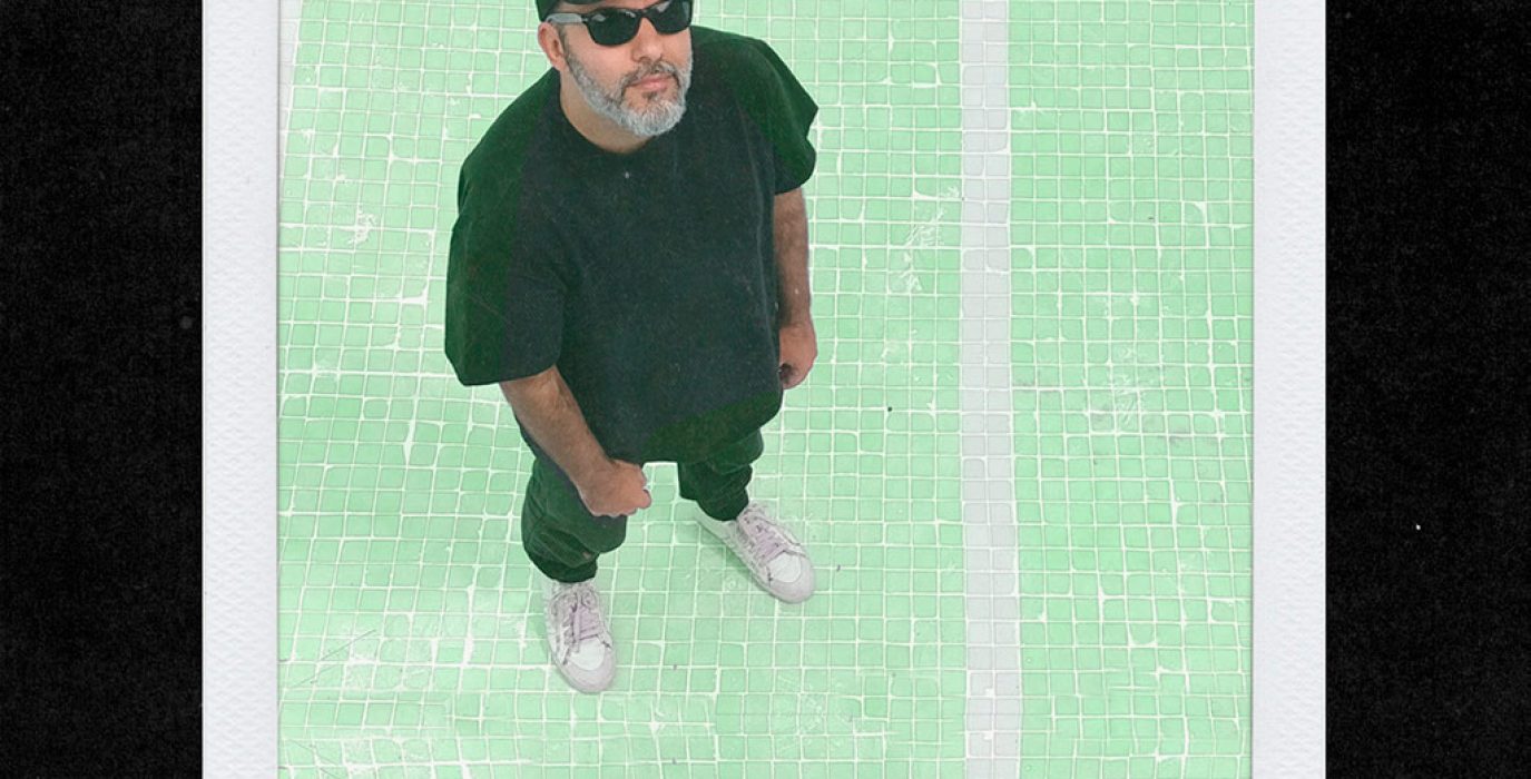 DJ2D2 con gorra y gafas de sol mirando hacia arriba con fondo verde, nuevo dj de la fiesta fokin massive