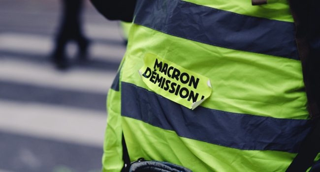Un chaleco amarillo donde se lee 'Macron dimisión' en francés en una marcha de la izquierda francesa