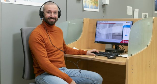 uno de los asistentes de atención telefónica en su puesto de trabajo con los cascos puestos