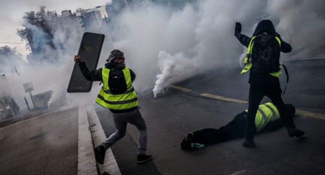 Dos manifestantes tratan de proteger a un tercero herido.