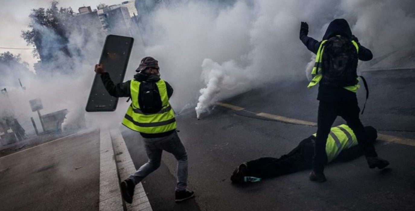 Dos manifestantes tratan de proteger a un tercero herido.