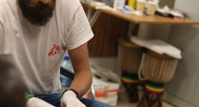 Luca Pigozzi realiza una cura a una personas rescatada que presenta una infección en una pierna causada por la exposición a condiciones de vida insalubres durante un período prolongado de tiempo. © Hannah Wallace Bowman/ MSF